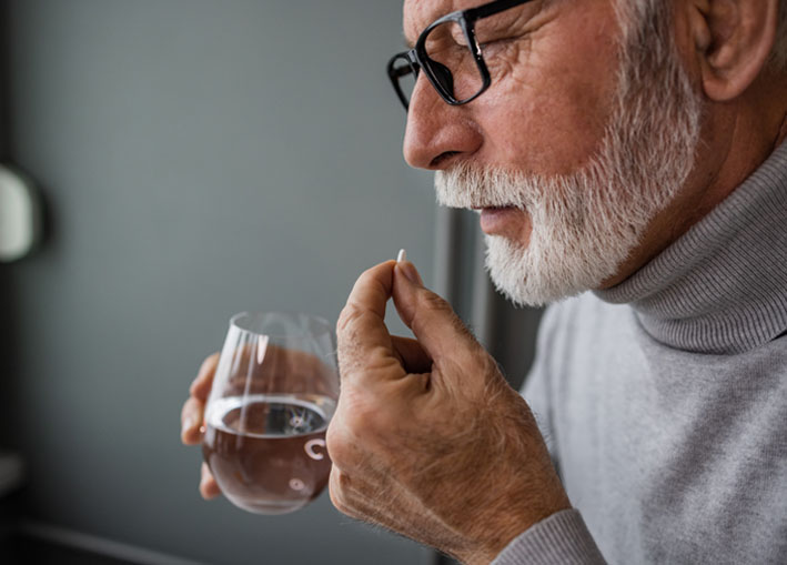 Photo of man taking medication with a glass of water