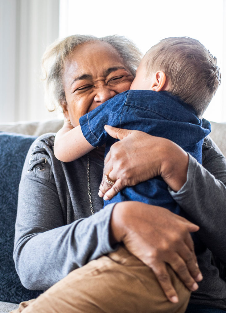 Photo of grandmother smiling while hugging grandson