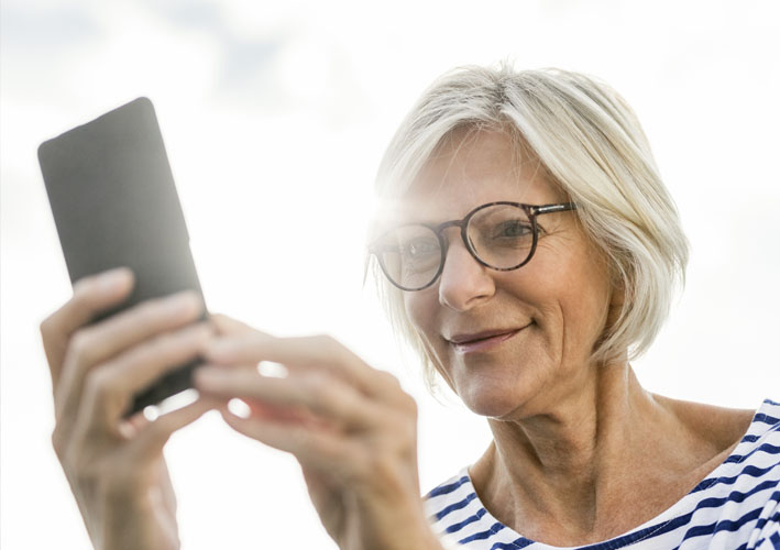 Photo of elderly woman smiling while looking at her phone