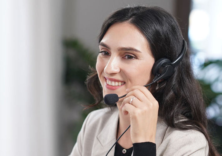 Photo of woman listening on a headset while smiling